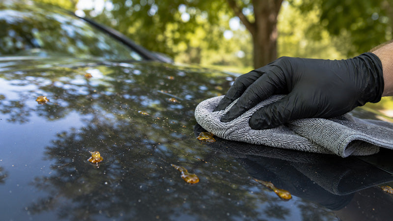 Résine d’arbre sur carrosserie de voiture noire nettoyée avec une microfibre
